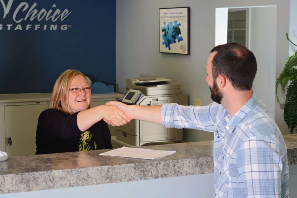 woman shaking hands with man over the welcome desk counter